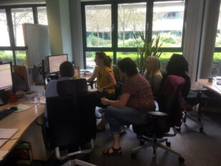 A team of technology experts gathered around a screen.