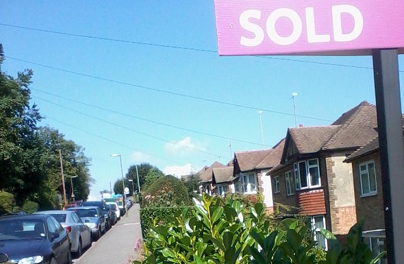 Residential street with a 'Sold' sign in the foreground.