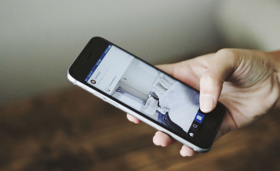 Smartphone user holds phone in hand. screen showing image of a bedroom.