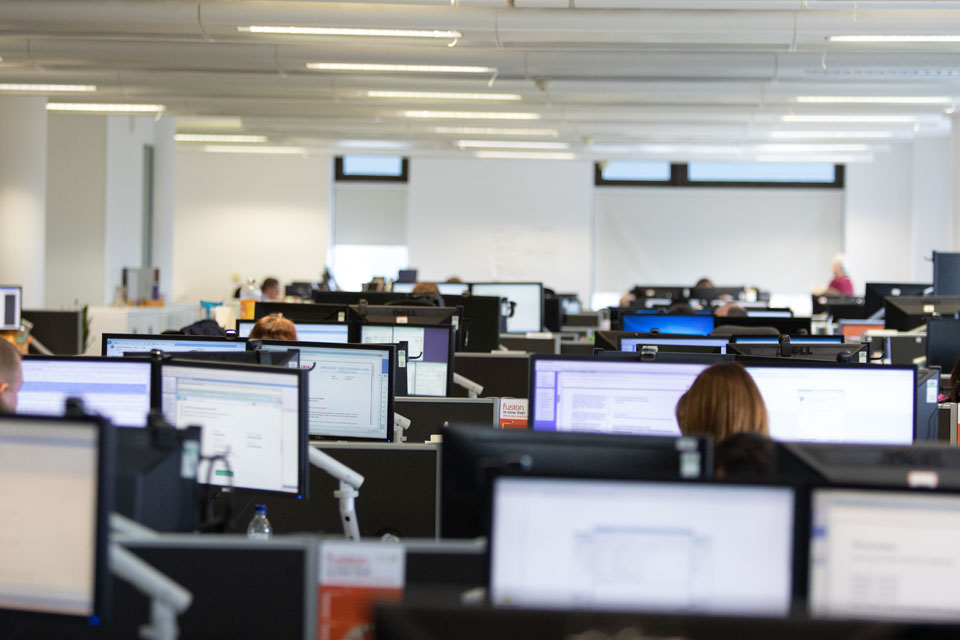 Rows of screens in an office with people working at them.