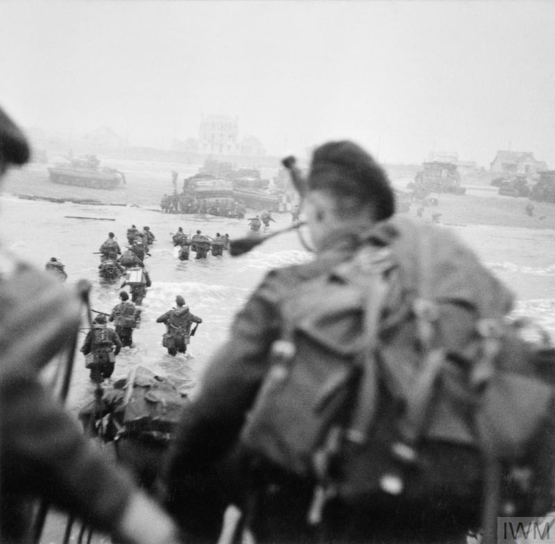 Commandos disembark from a landing craft onto a beach.