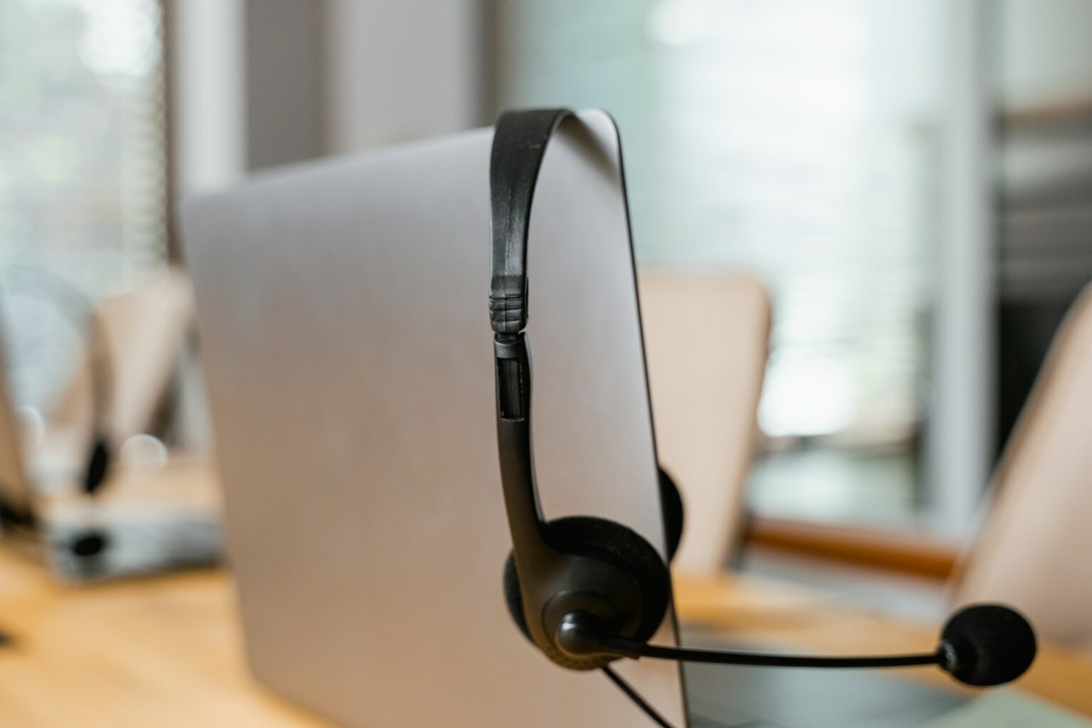 A headset rests on a laptop screen that is popped open.
